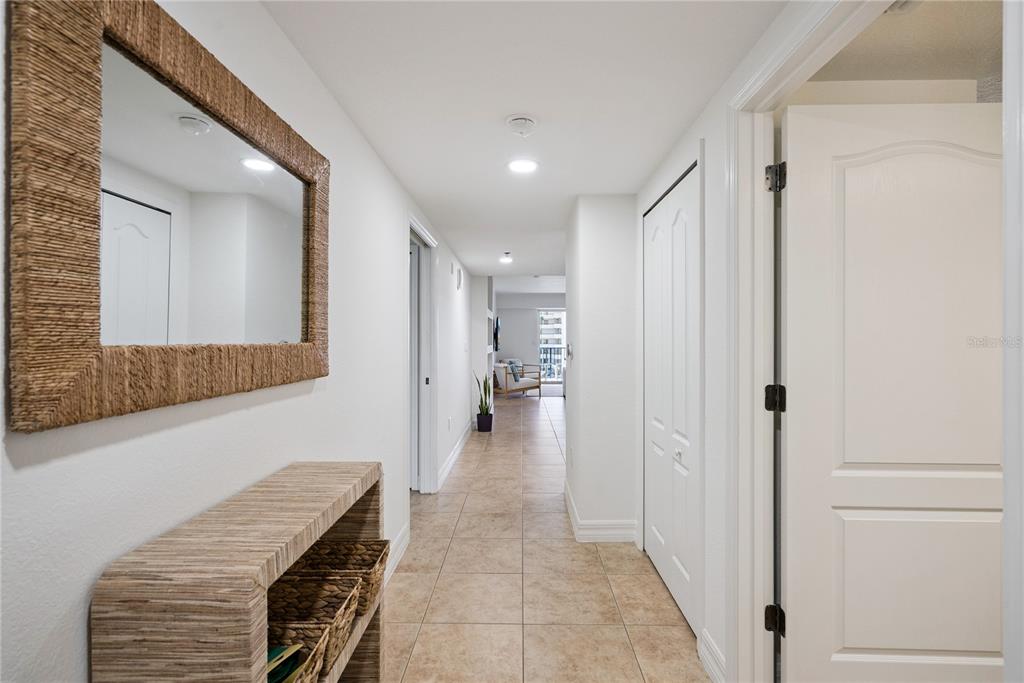 A hallway with tile flooring, a mirror, a console table, and white interior doors — 5300 S ATLANTIC AVENUE UNIT 13-604, NEW SMYRNA BEACH, FL