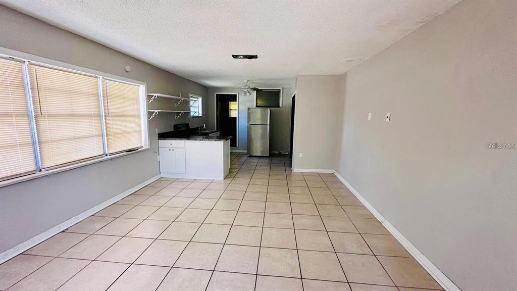 A kitchen with tile floors, stainless steel sink, and open living area with ceiling fan — 1310 N COMBEE ROAD UNIT 7, LAKELAND, FL