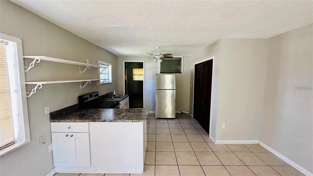 An open-concept kitchen and living area features light tile flooring and white cabinetry — 1310 N COMBEE ROAD UNIT 7, LAKELAND, FL