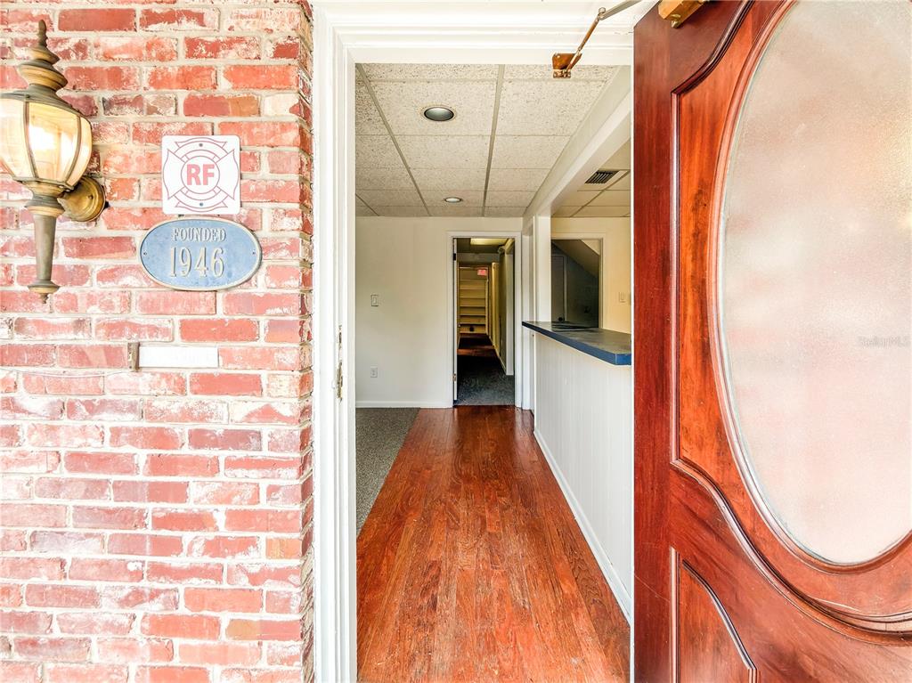 A brick exterior wall with a vintage sign leads into an interior with wood flooring — 703 E PINE STREET, ORLANDO, FL
