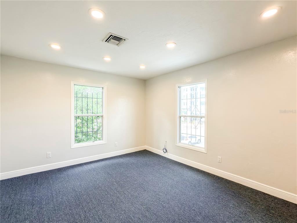 An empty bedroom features beige walls, dark gray carpeting, recessed lighting, and two windows — 703 E PINE STREET, ORLANDO, FL