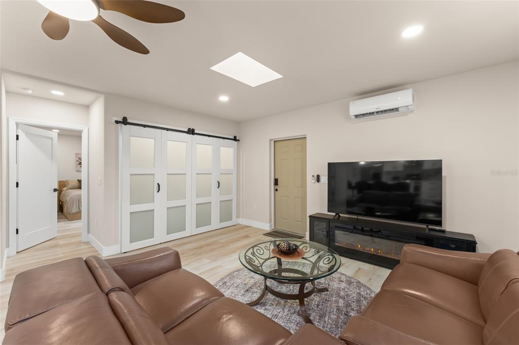 A living room features brown leather sofas, a glass coffee table, and white sliding barn doors — 5028 AUTUMN RIDGE LANE, WINDERMERE, FL