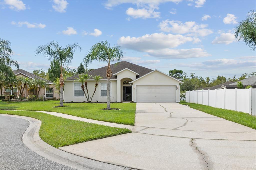 A single-story house with a white stucco exterior, a two-car garage, and a concrete driveway — 14424 BABYLON WAY, ORLANDO, FL