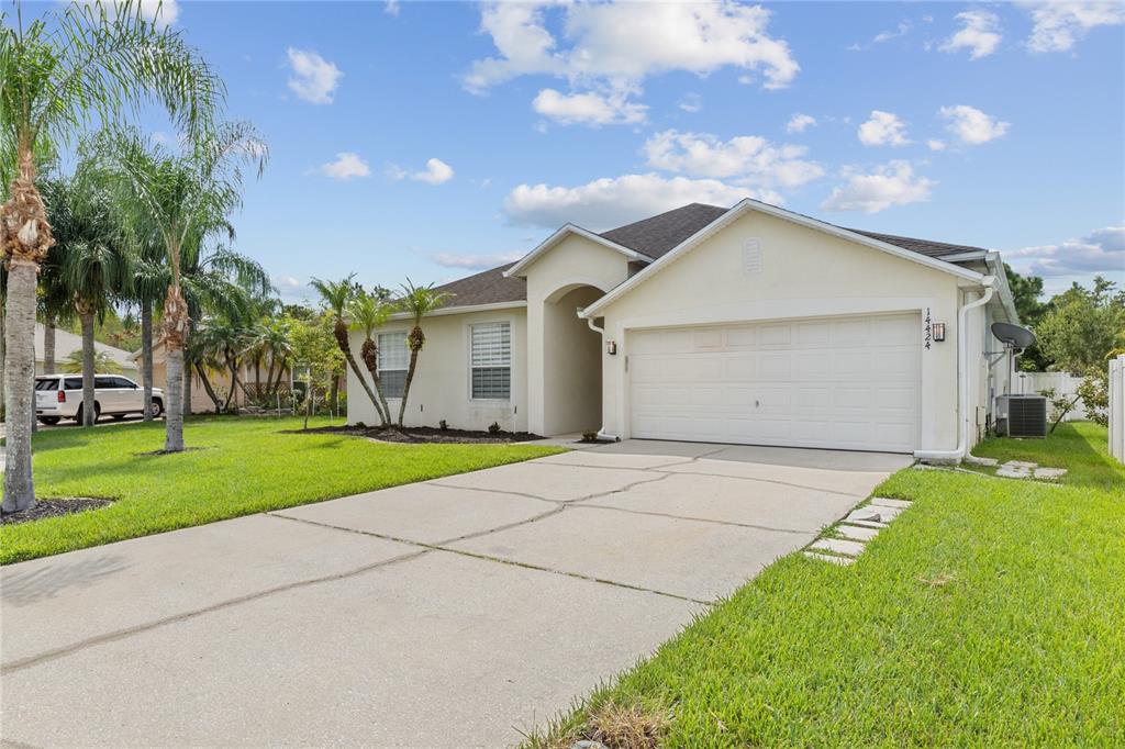A single-story house with a white stucco exterior, a two-car garage, and a concrete driveway — 14424 BABYLON WAY, ORLANDO, FL