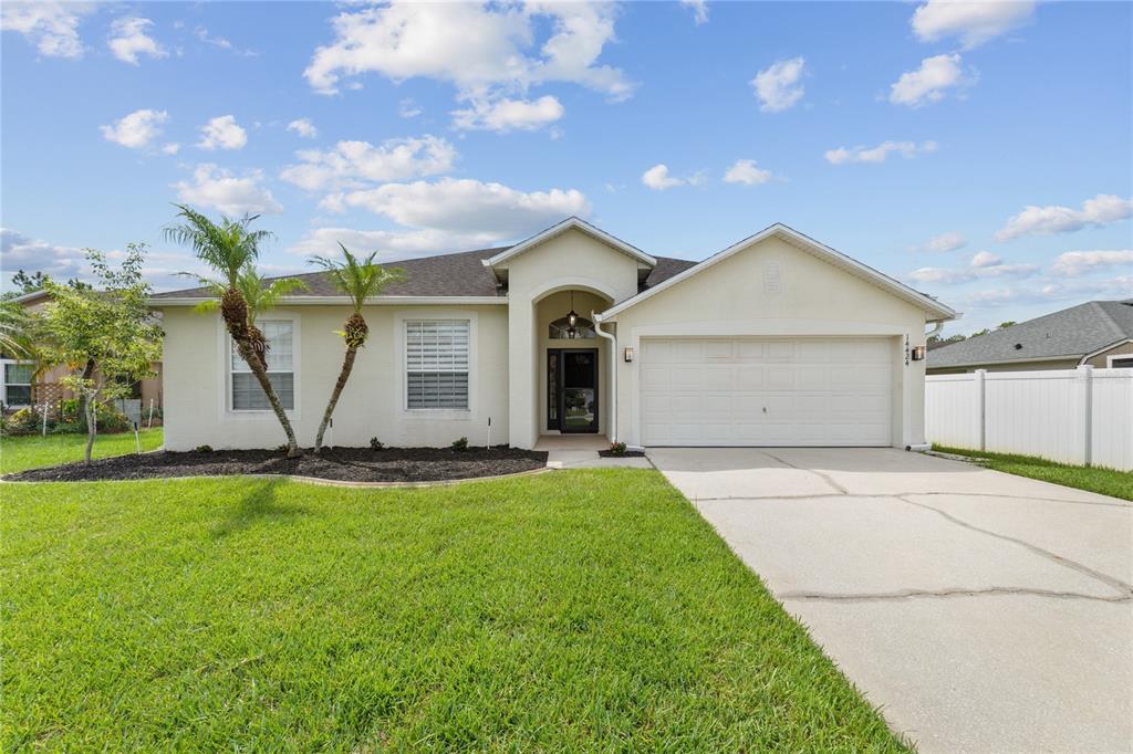 A single-story house with a beige stucco exterior, a two-car garage, and a front lawn — 14424 BABYLON WAY, ORLANDO, FL