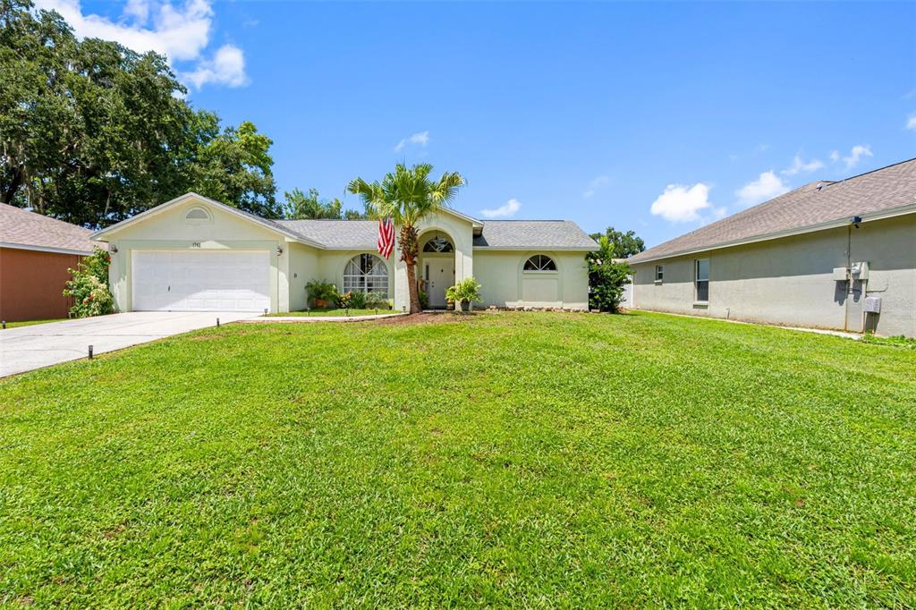 A single-story house with a white garage, a palm tree, and a grassy front lawn — 1742 STAYSAIL DRIVE, VALRICO, FL