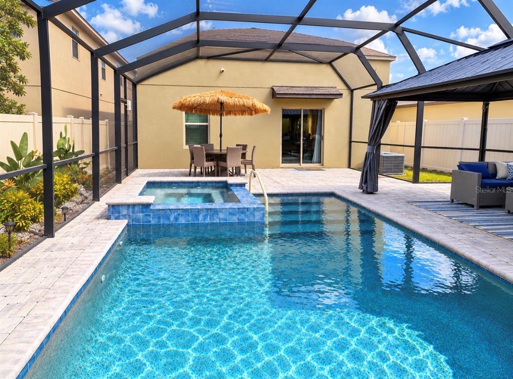 A screened-in patio features a swimming pool, a hot tub, and outdoor dining furniture — 15705 FORT ISLAND PLACE, SUN CITY CENTER, FL