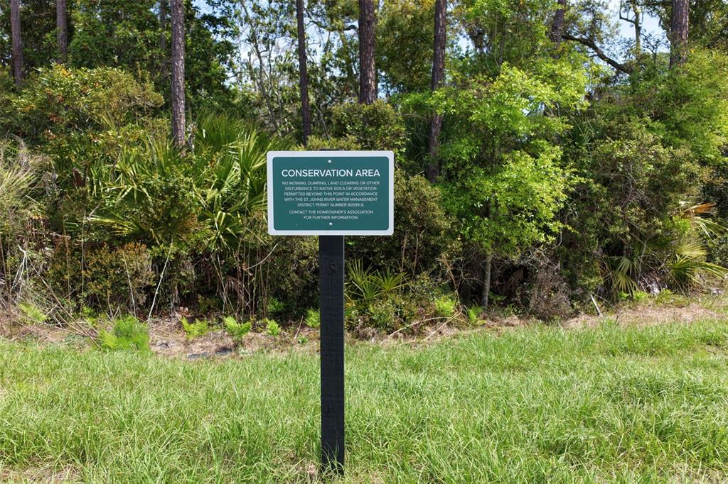 A sign marking a conservation area stands in front of a wooded lot — 222 STILLWATER DRIVE, FLAGLER BEACH, FL