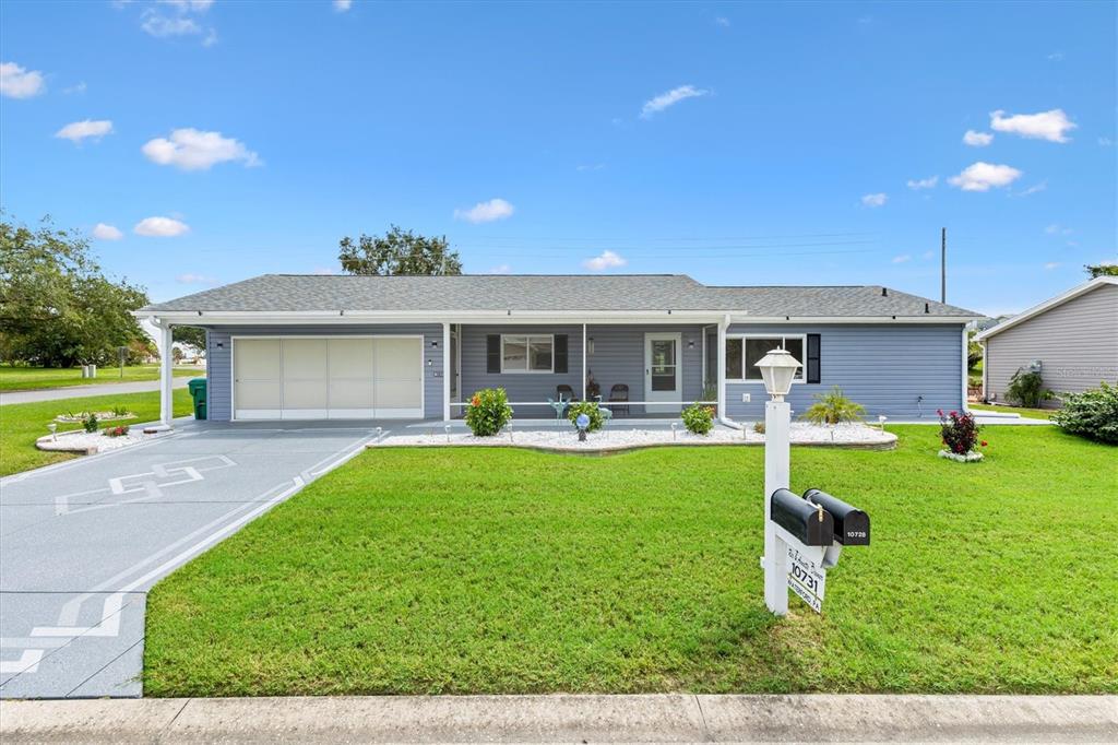 A single-story blue house with a garage, a front porch, and a manicured lawn — 10731 SE 174TH LOOP, SUMMERFIELD, FL