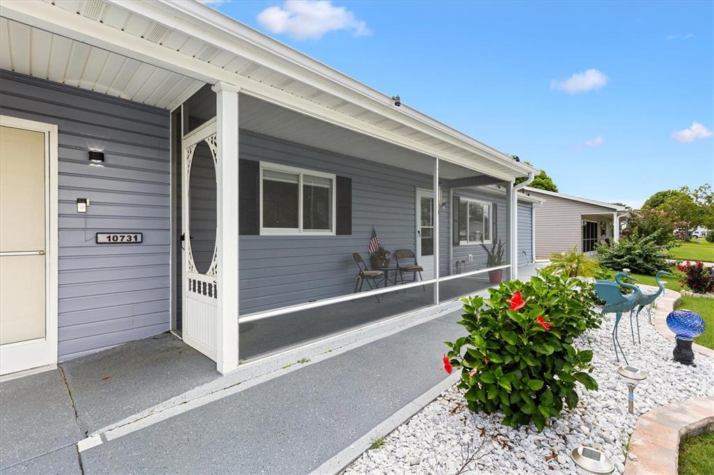 A light blue house features a screened-in porch, white trim, and a white rock garden — 10731 SE 174TH LOOP, SUMMERFIELD, FL