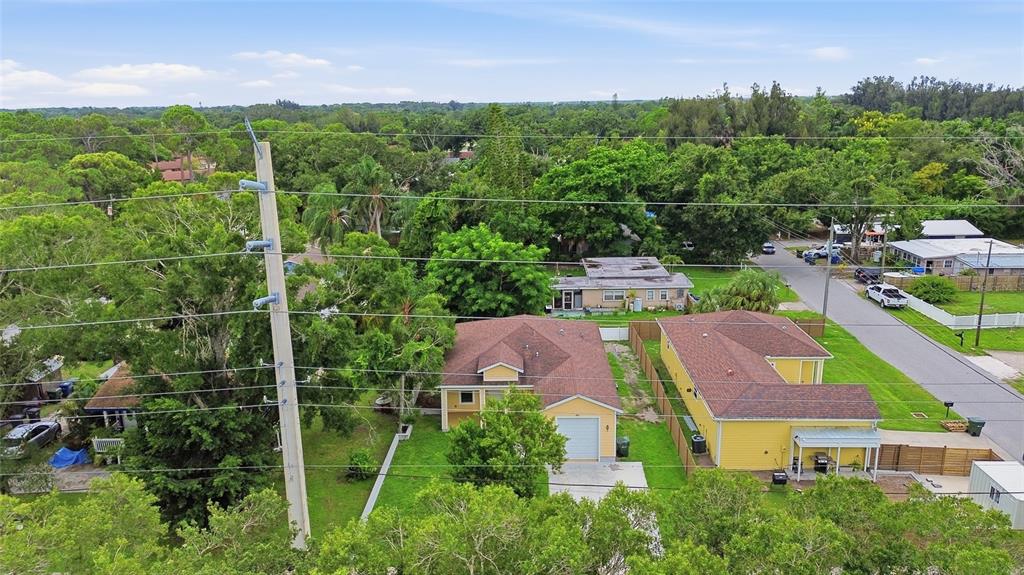 An aerial view of two yellow houses with brown roofs situated in a wooded neighborhood — 4510 WILKINSON ROAD, SARASOTA, FL