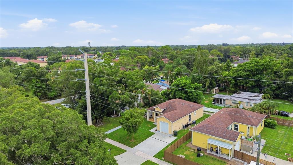 An aerial view shows two yellow houses with brown roofs surrounded by trees and power lines — 4510 WILKINSON ROAD, SARASOTA, FL