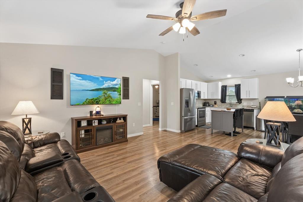 A living room with wood-look flooring, a leather sectional, and an open-concept kitchen — 8288 SW SUNNYBREEZE ROAD, ARCADIA, FL