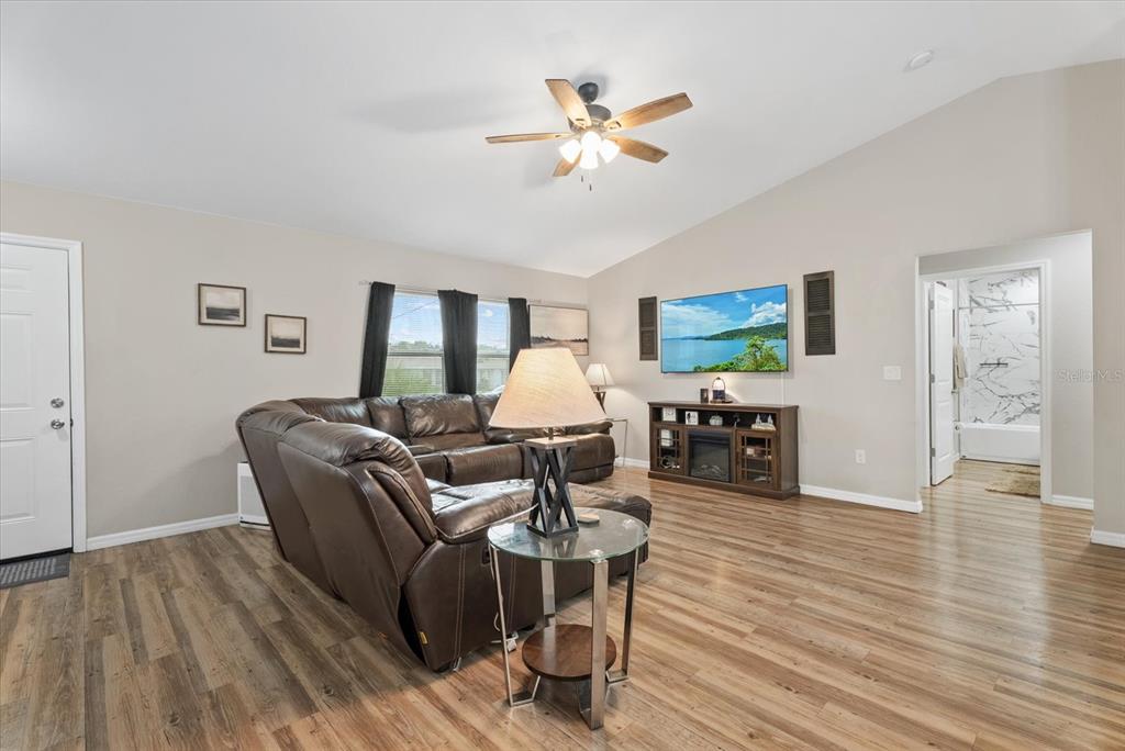 A living room features a brown leather sectional, a glass side table, and a wall-mounted television — 8288 SW SUNNYBREEZE ROAD, ARCADIA, FL