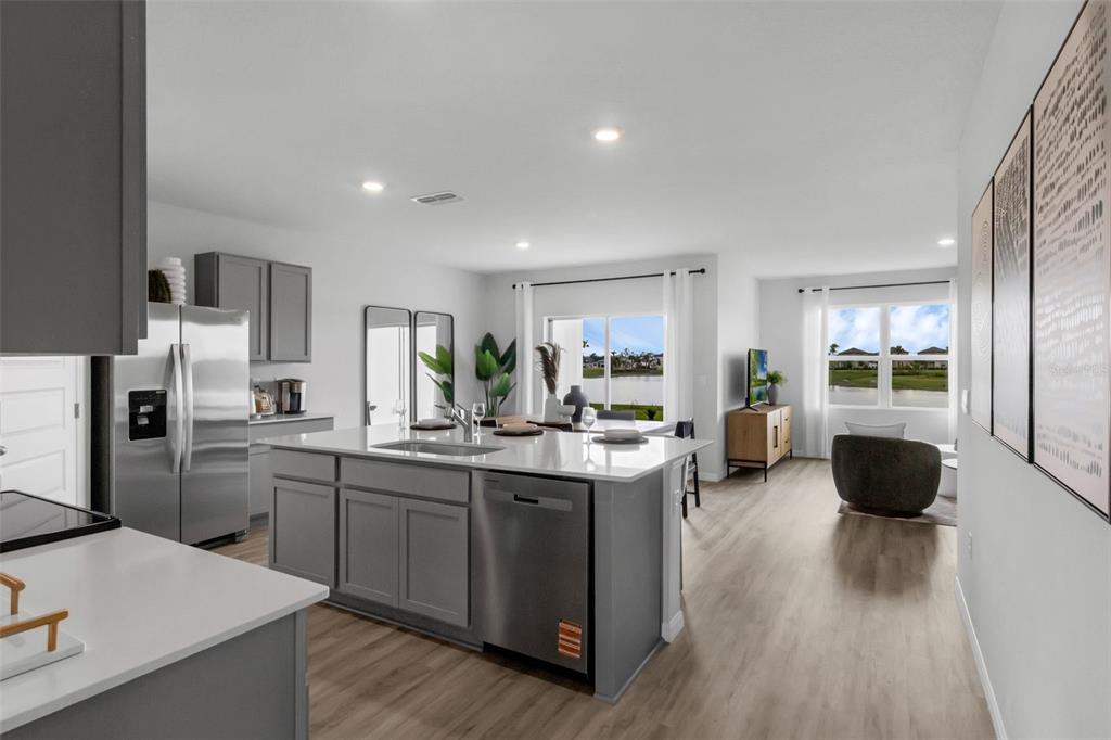 A modern kitchen with a large island overlooks a living area with a water view — 7864 FORREST FOX WAY, LAKELAND, FL