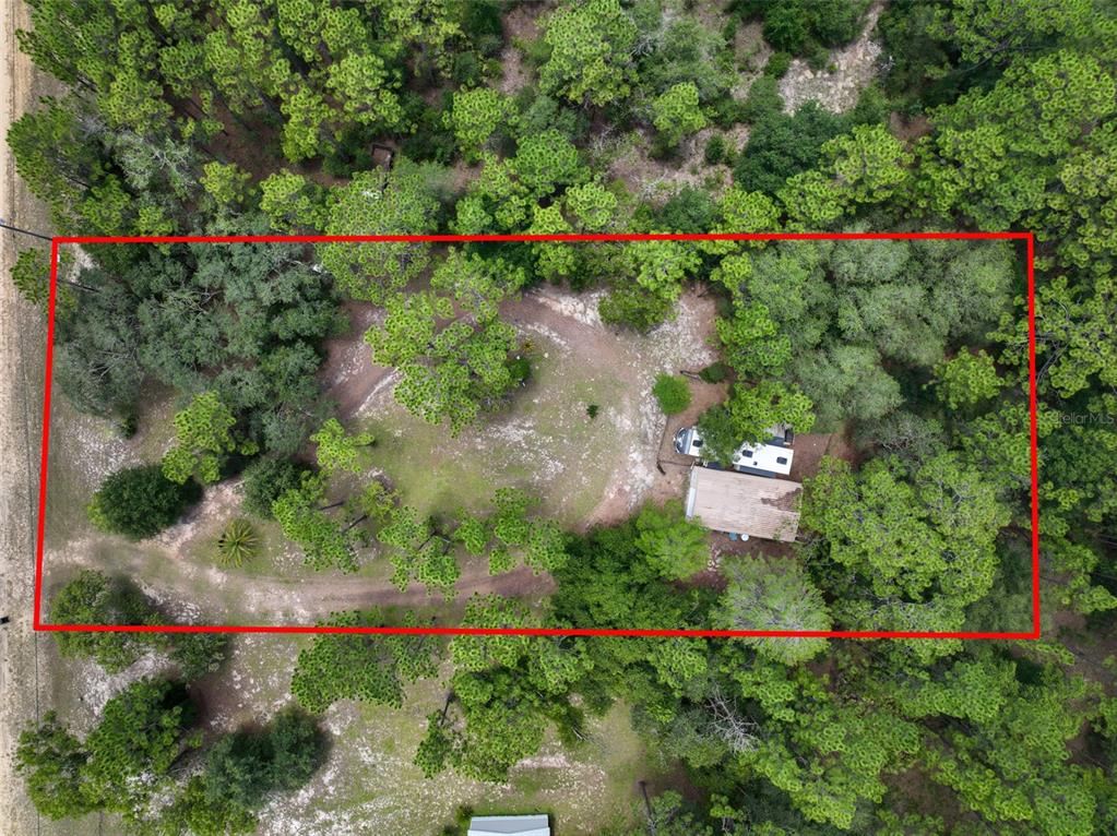 An aerial view shows a wooded lot with a driveway, a small building, and a camper — 5620 LASSEN STREET, KEYSTONE HEIGHTS, FL