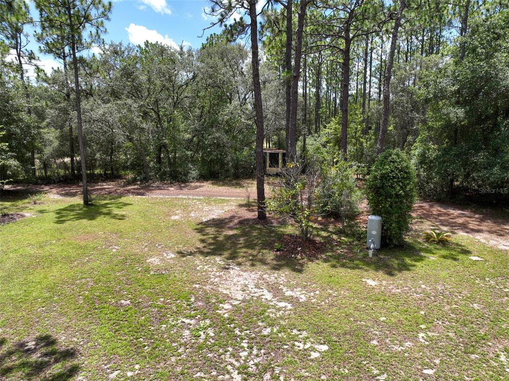A grassy backyard features scattered trees, a small shed, and a propane tank — 5620 LASSEN STREET, KEYSTONE HEIGHTS, FL