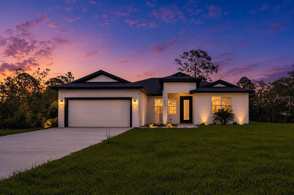 A modern single-story house with a white stucco exterior, dark trim, and a two-car garage — 551 DOWLING CIRCLE, LADY LAKE, FL