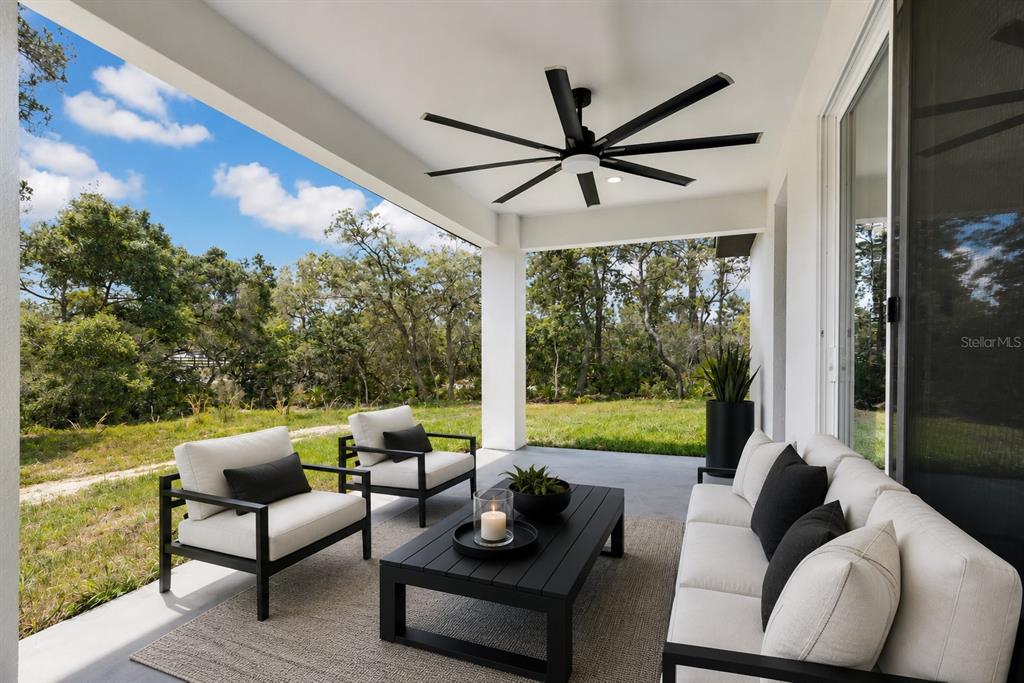 A covered patio features a black ceiling fan, outdoor furniture, and a view of trees — 551 DOWLING CIRCLE, LADY LAKE, FL