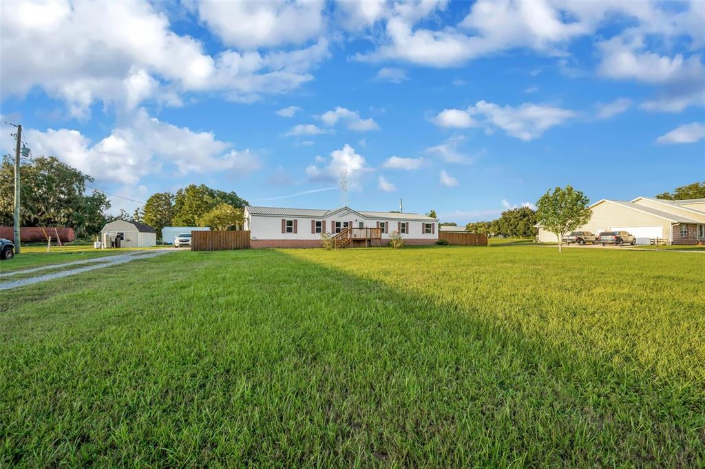 A single-story manufactured home sits on a large grassy lot under a blue sky — 3858 E KNIGHTS GRIFFIN ROAD, PLANT CITY, FL