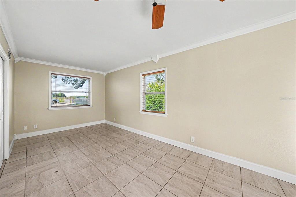 An empty room with beige walls, tile flooring, two windows, and a ceiling fan — 10118 114TH TERRACE, LARGO, FL
