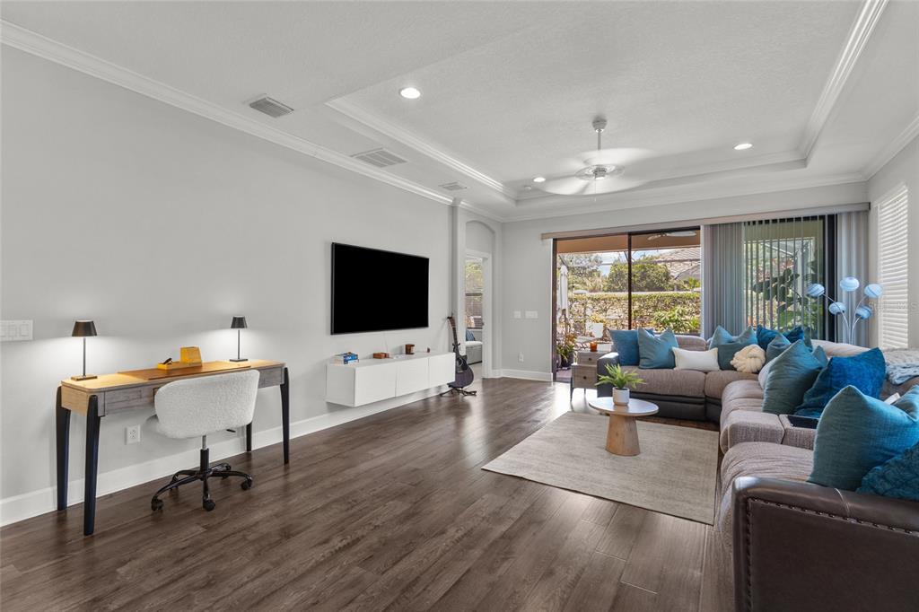 A living room features a large sectional sofa, a wall-mounted television, and sliding glass doors — 5019 SAVONA RUN, BRADENTON, FL