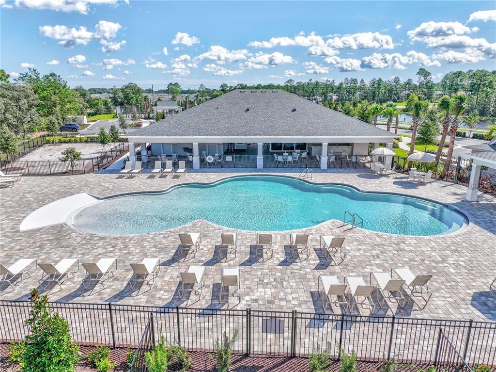 An outdoor swimming pool with lounge chairs sits in front of a community clubhouse building — 1561 LAKE BANK LANE, DELAND, FL