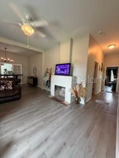 A living room features light wood-look flooring, a white fireplace, and a ceiling fan — 1003 NE 2ND STREET, MULBERRY, FL