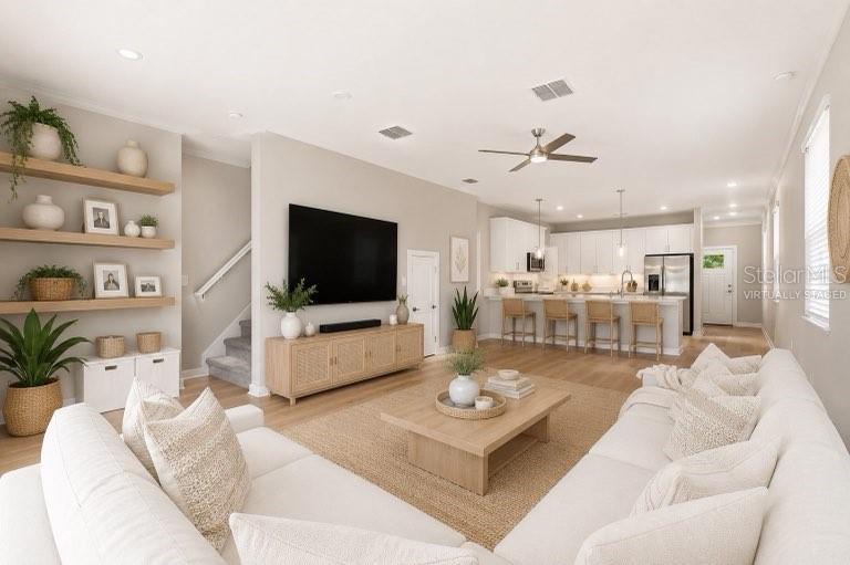 A bright, open-concept living room and kitchen featuring light wood floors and neutral furniture — 2704 W GRAY STREET UNIT A, TAMPA, FL