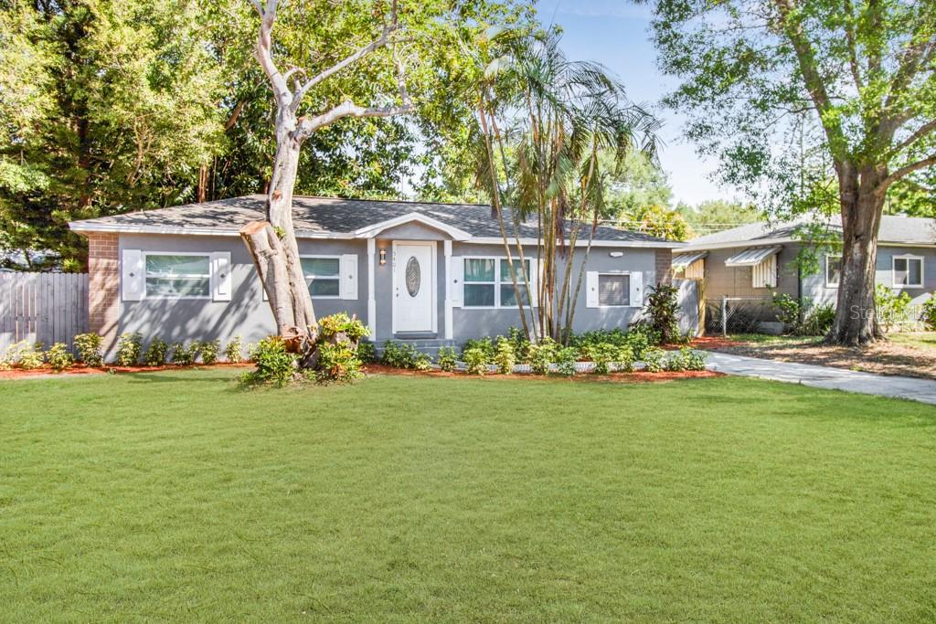 A single-story gray house with white shutters and a large front lawn under sunny skies — 5401 43RD TERRACE N, ST PETERSBURG, FL
