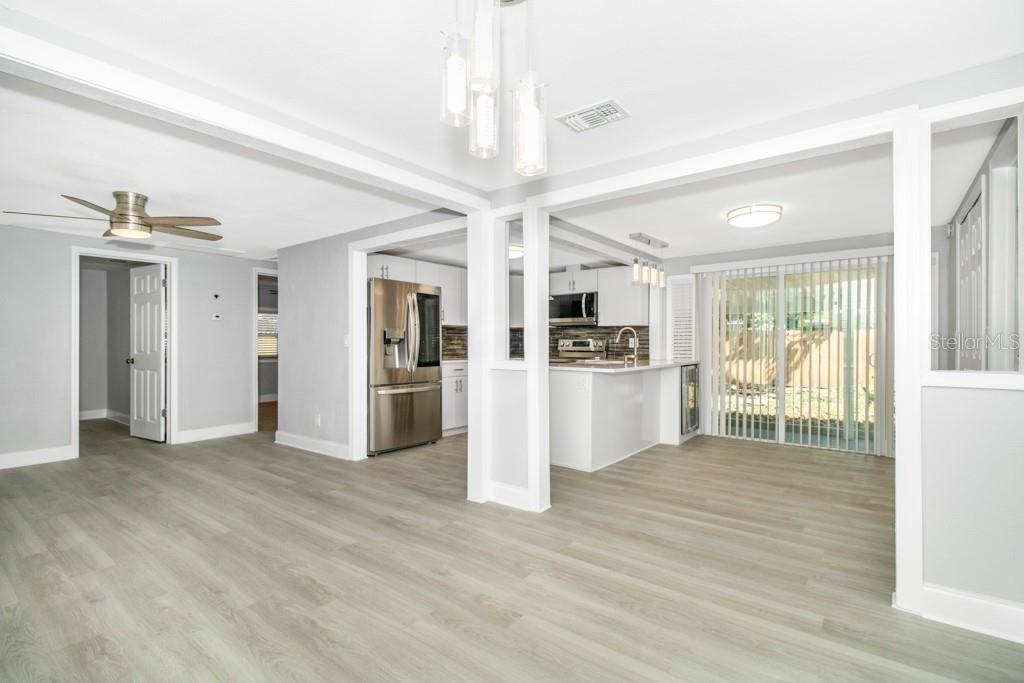 An open-concept living and dining area features light wood-look flooring and a modern kitchen — 5401 43RD TERRACE N, ST PETERSBURG, FL