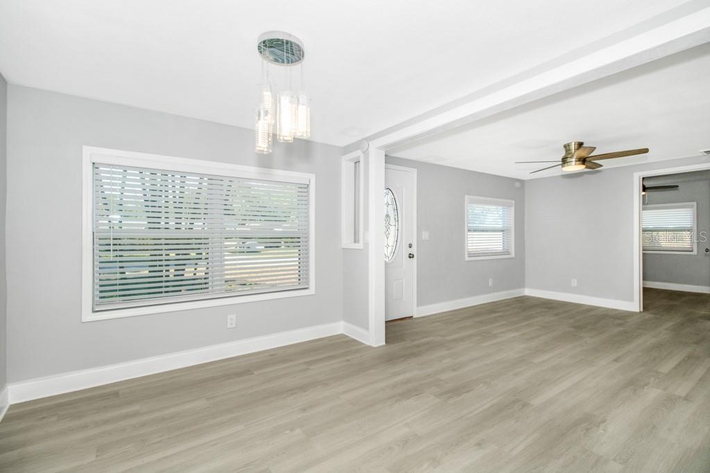 An empty room with light gray walls, wood-look flooring, a ceiling fan, and a chandelier — 5401 43RD TERRACE N, ST PETERSBURG, FL