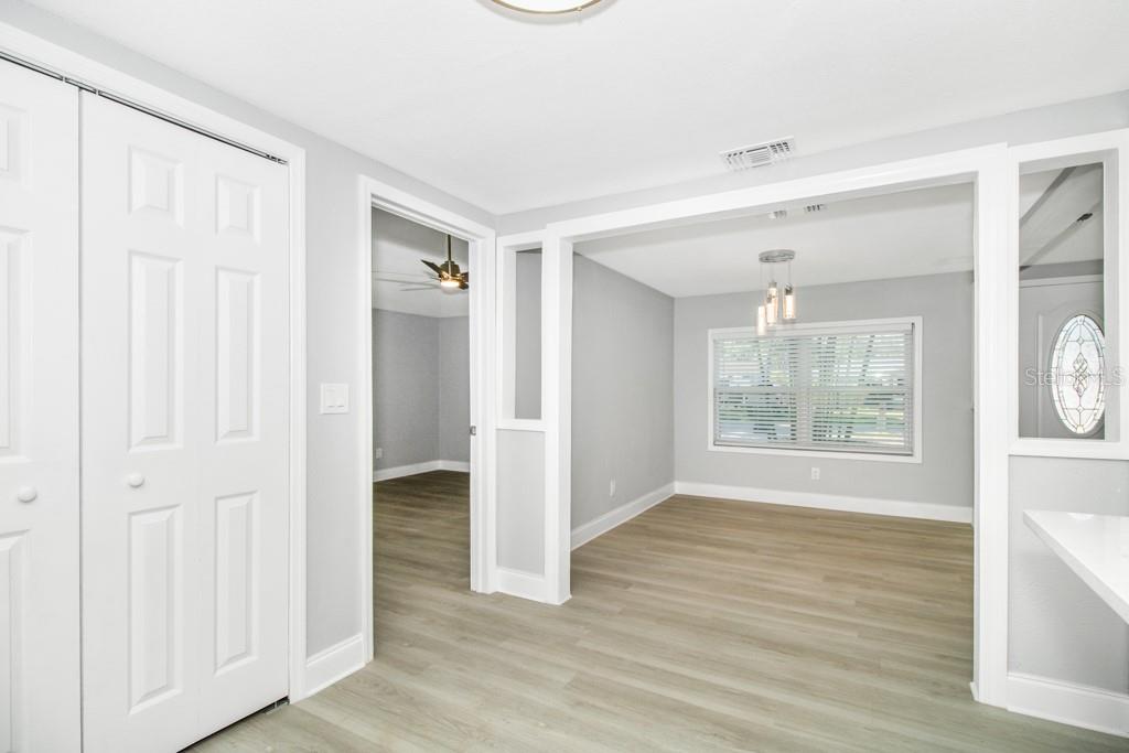 A bright room with light wood-look flooring, white trim, and a view into another room — 5401 43RD TERRACE N, ST PETERSBURG, FL