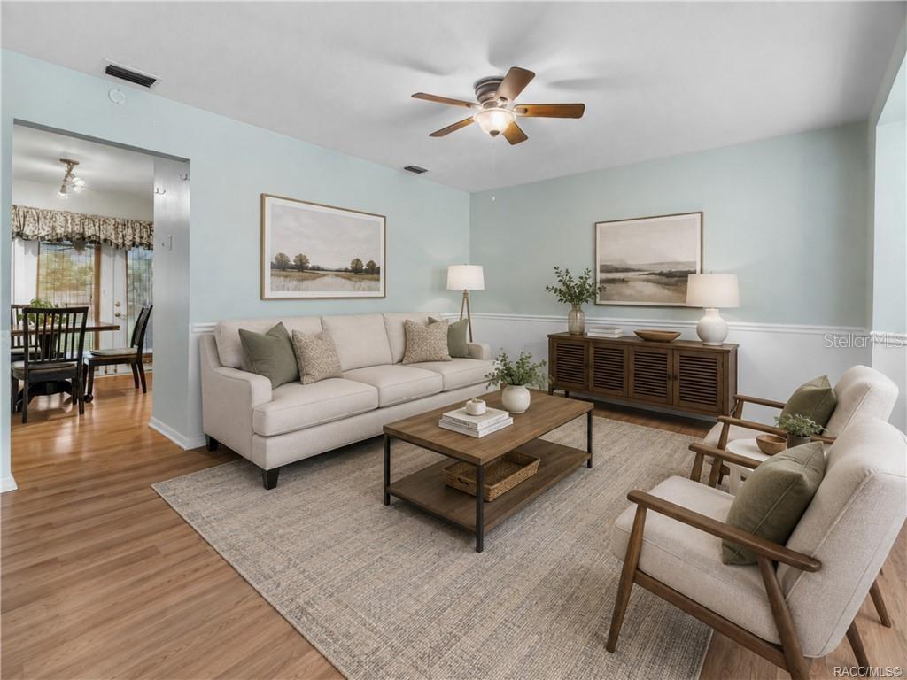 A living room features a beige sofa, two armchairs, a coffee table, and light blue walls — 6094 E PENROSE STREET, INVERNESS, FL