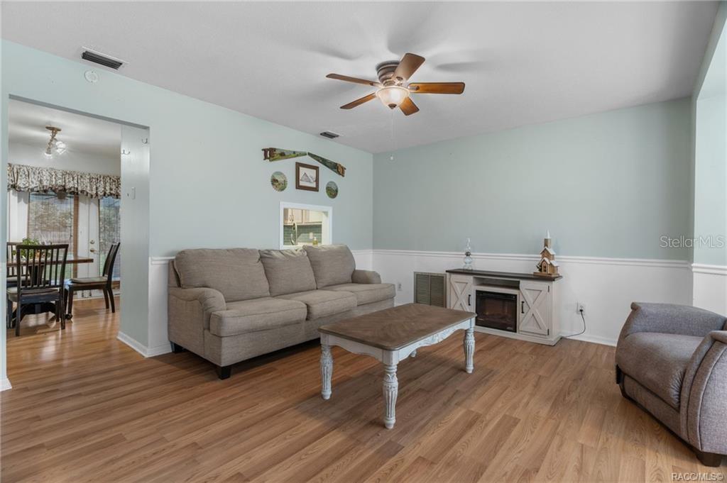 A living room features light blue walls, a gray sofa, a coffee table, and wood flooring — 6094 E PENROSE STREET, INVERNESS, FL