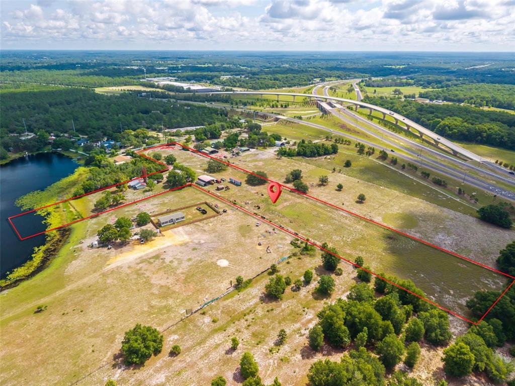 An aerial view shows a large, grassy plot of land outlined in red near a lake — 3480 ONDICH ROAD, APOPKA, FL