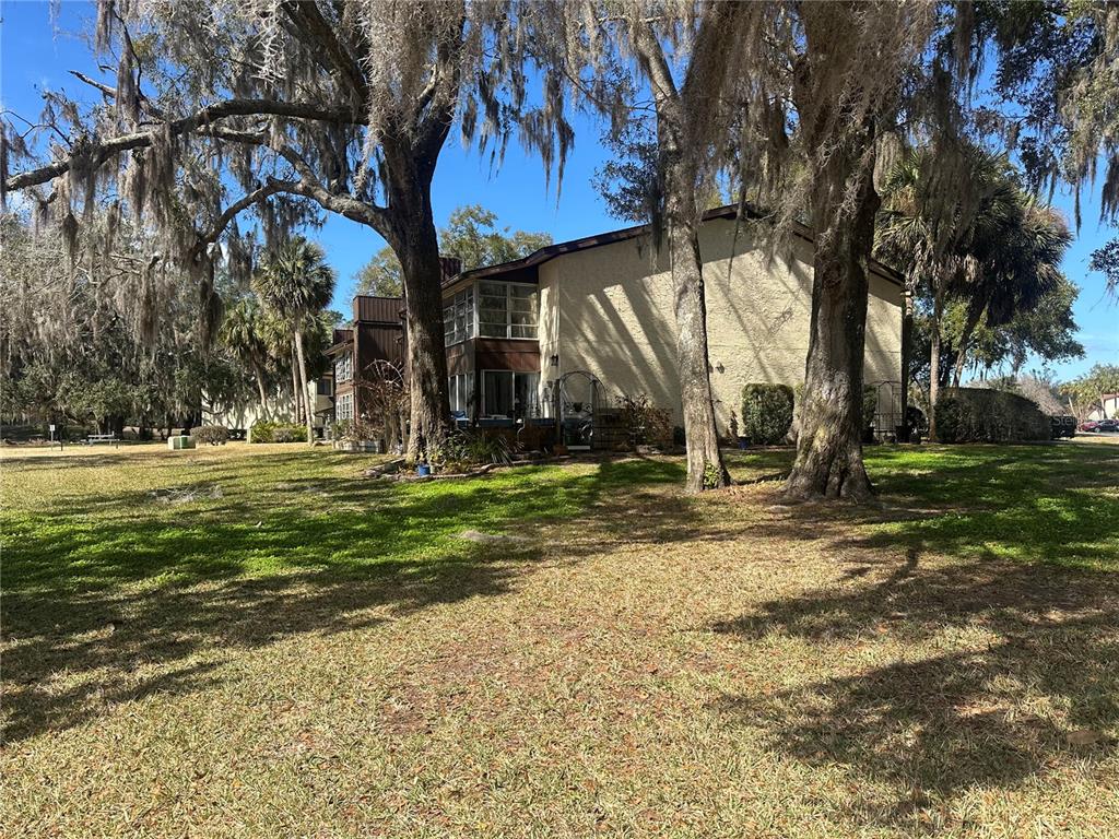 A two-story building with stucco siding stands behind large trees draped in Spanish moss — 763 MIDWAY DRIVE UNIT B, OCALA, FL