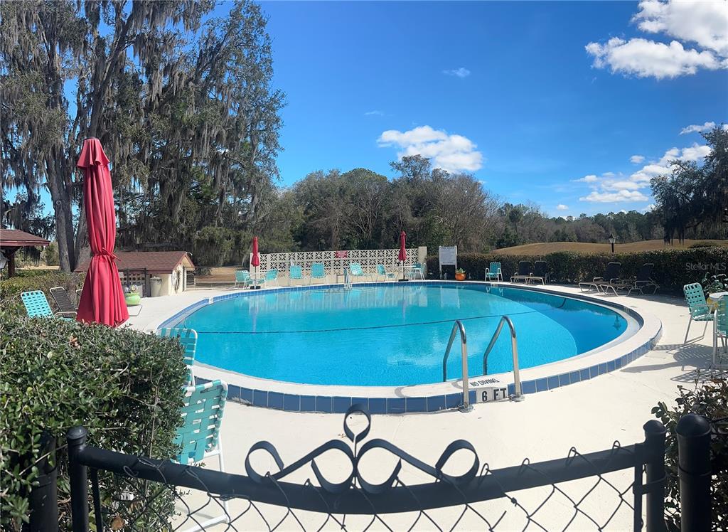 A circular outdoor swimming pool is surrounded by lounge chairs, umbrellas, and a chain-link fence — 763 MIDWAY DRIVE UNIT B, OCALA, FL