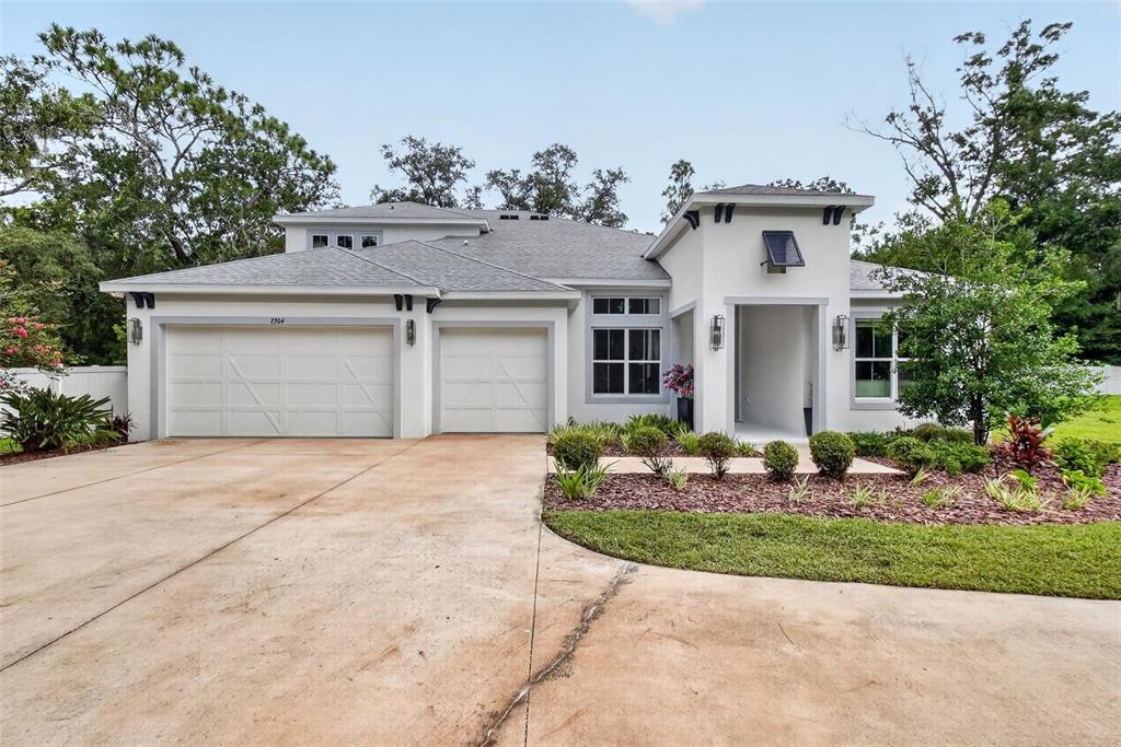 A single-story house with a white stucco exterior, a three-car garage, and a landscaped yard — 2304 CLEMENT ROAD, LUTZ, FL