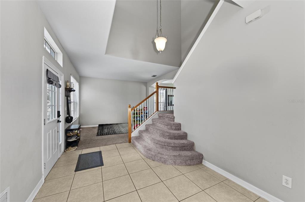 An entryway features a tiled floor, a carpeted staircase, and a high ceiling with lighting — 5224 58TH TERRACE E, BRADENTON, FL