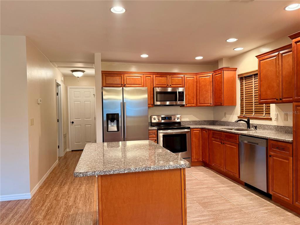 A kitchen features wood cabinets, stainless steel appliances, granite countertops, and a central island — 9940 SW 102ND LANE, OCALA, FL