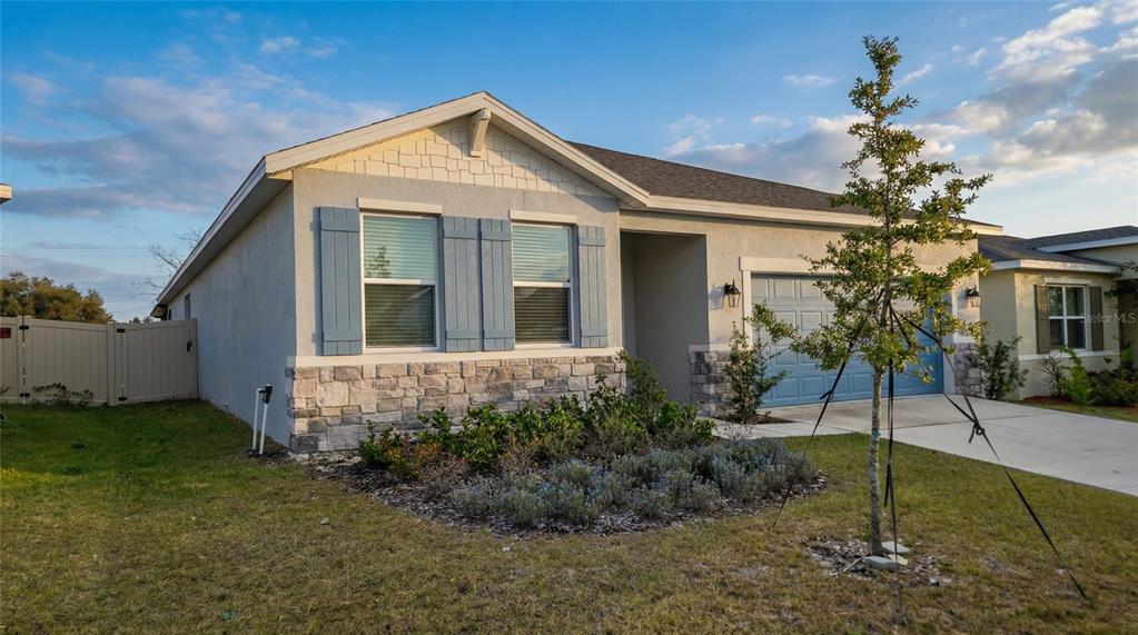 A single-story house with a blue garage door, stone veneer, and blue shutters — 693 CROWN ROSE DRIVE, EAGLE LAKE, FL