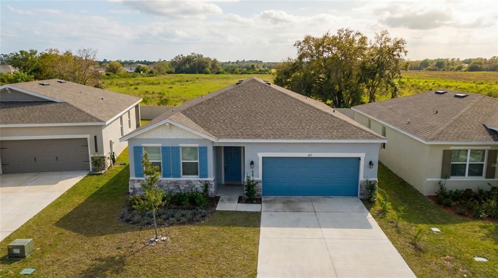 An aerial view of a single-story suburban house with a blue garage and front door — 693 CROWN ROSE DRIVE, EAGLE LAKE, FL
