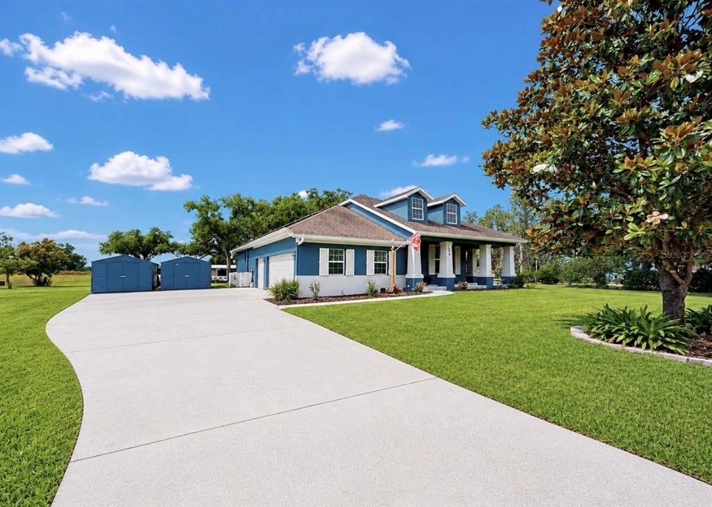 A blue and white house with a large concrete driveway and two detached storage sheds — 13101 DONE GROVEN DRIVE, DOVER, FL