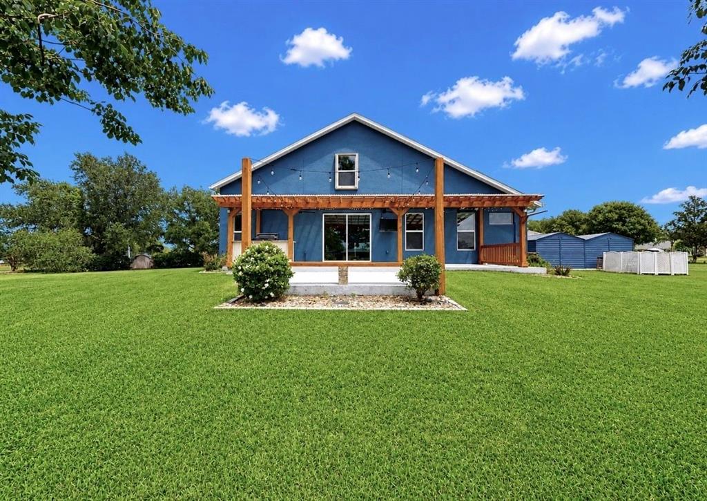 A blue house with a wooden pergola over a patio sits on a grassy lawn — 13101 DONE GROVEN DRIVE, DOVER, FL