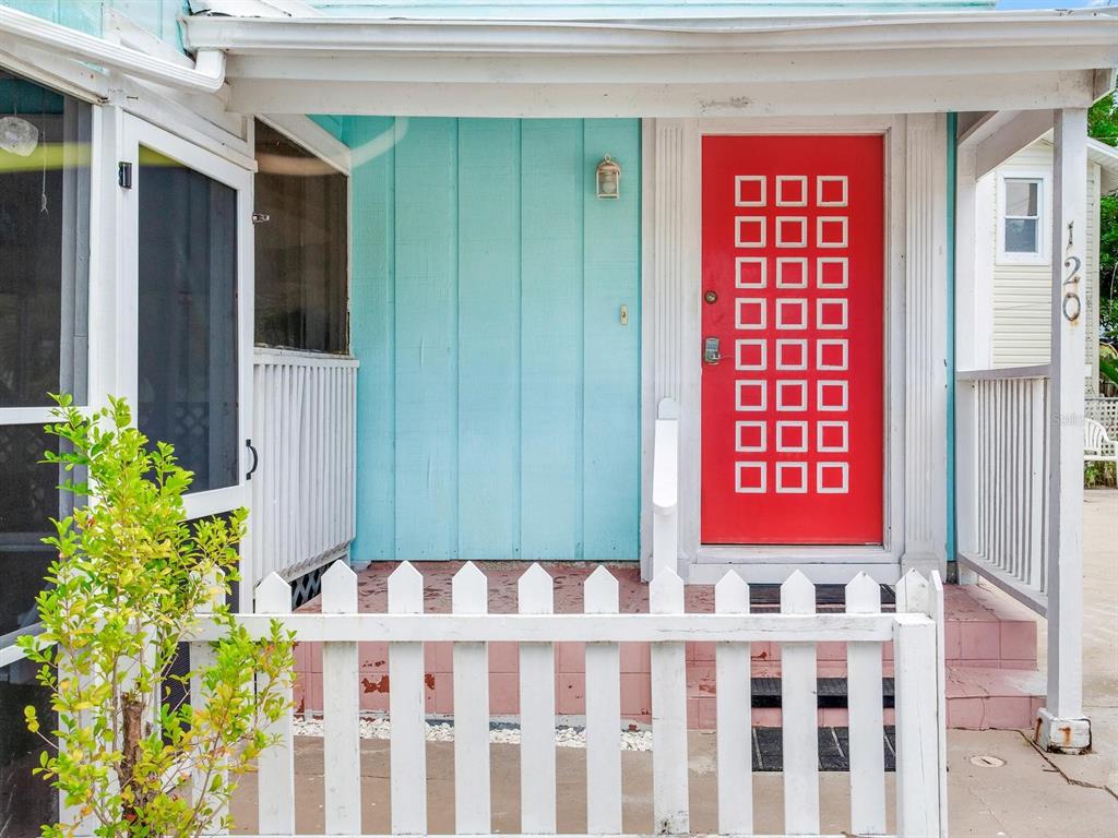 A bright red door with a grid of square windows sits on a turquoise porch — 120 93RD AVENUE, TREASURE ISLAND, FL