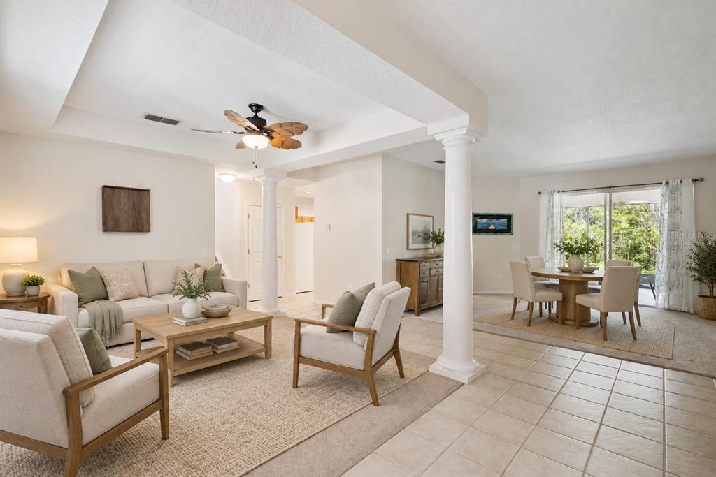 A living area with carpeted floors, white columns, a ceiling fan, and sliding glass doors — 2589 CORBYTON COURT, ORLANDO, FL