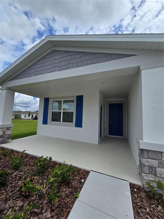 A front porch with a blue door, window shutters, and stone accents on the exterior — 1767 FOREMAN ROAD, EAGLE LAKE, FL