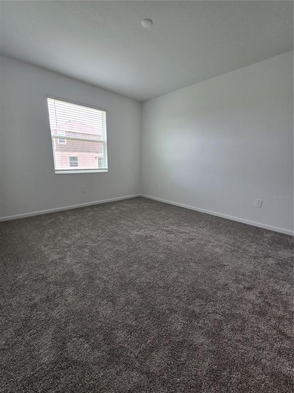 An empty bedroom features gray carpet, white walls, and a single window with blinds — 1767 FOREMAN ROAD, EAGLE LAKE, FL