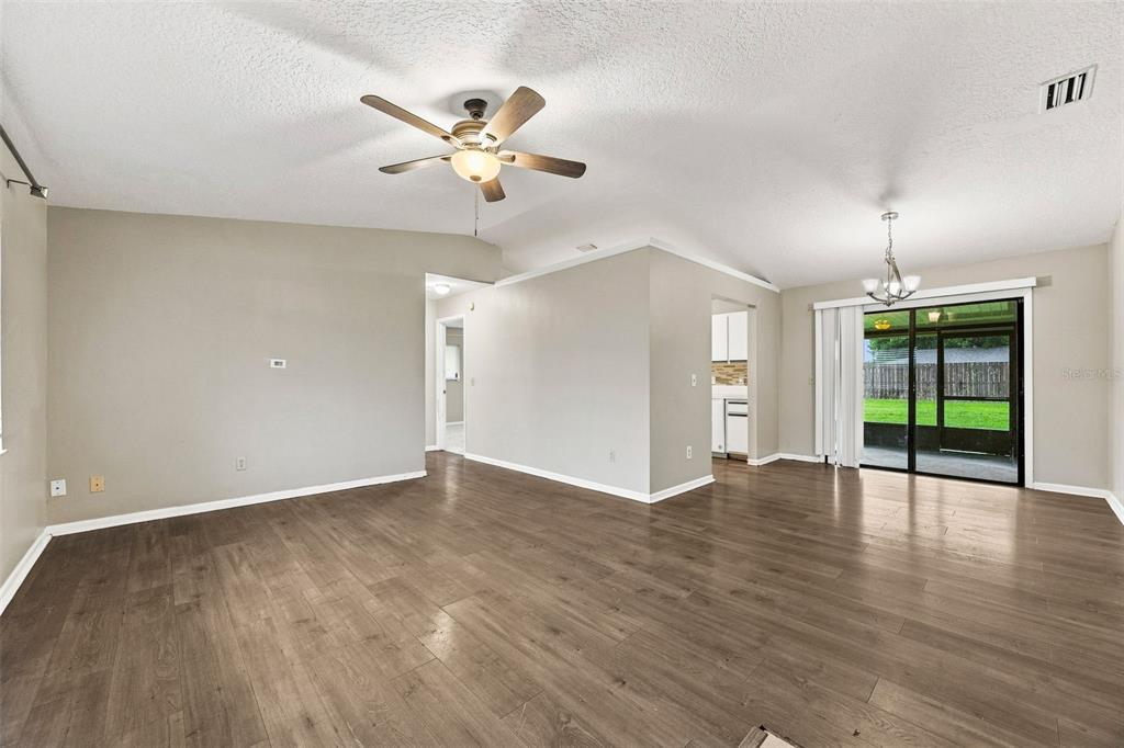 An empty living room with wood-look flooring, a ceiling fan, and sliding glass doors — 709 CUXHAVEN STREET NW, PALM BAY, FL